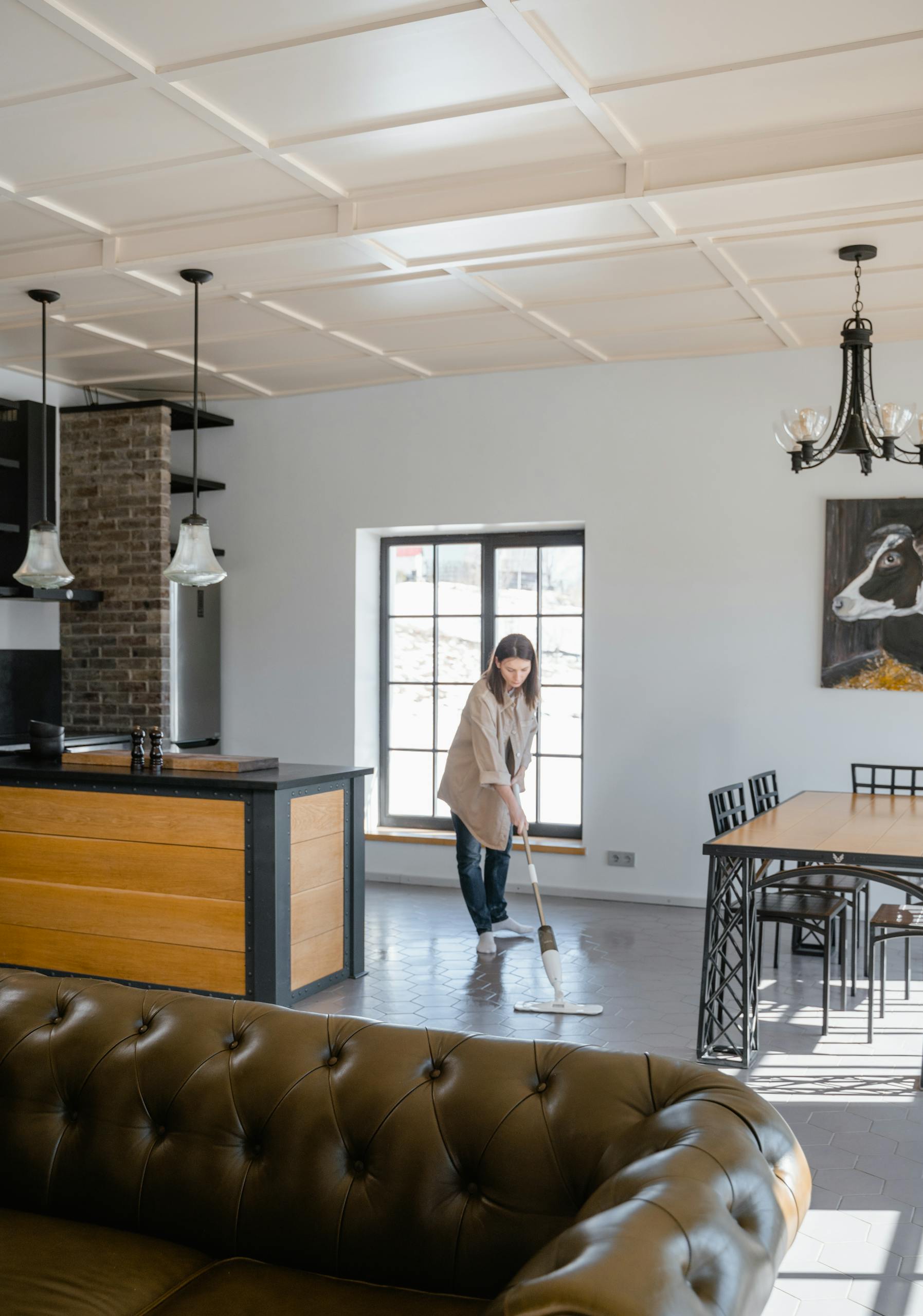 A modern living room interior with a woman mopping the floor, showcasing home cleanliness and interior design.